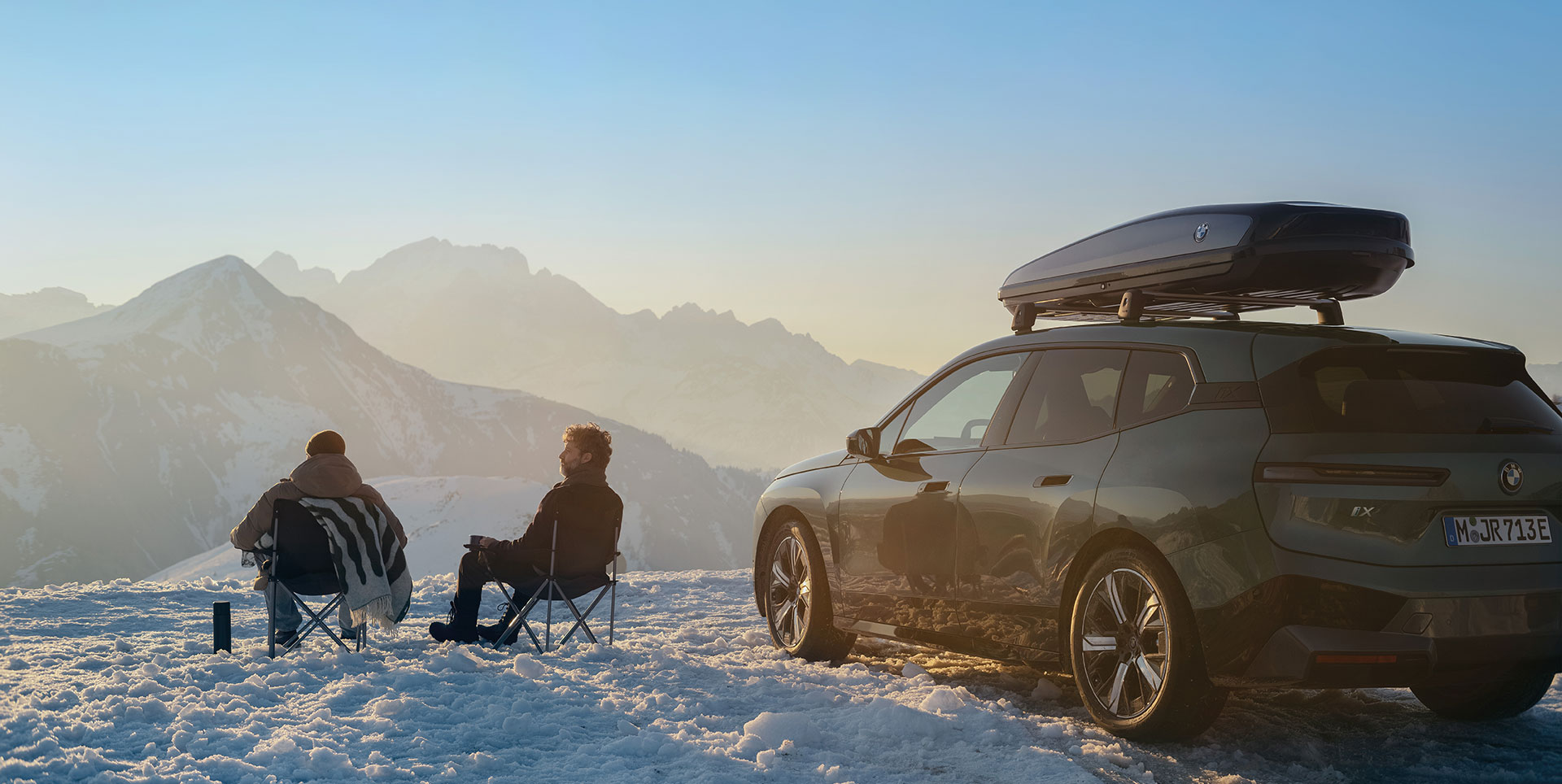Zwei Männer neben einem Fahrzeug im Schnee.